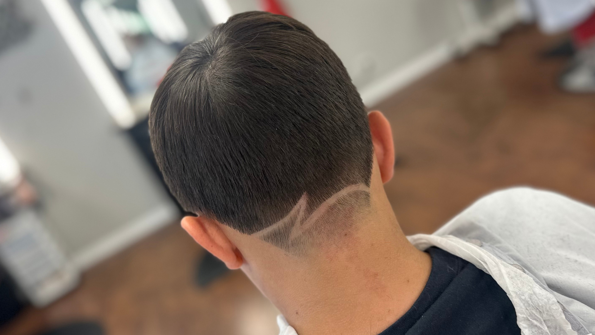 Back view of a persons head, showcasing a trendy short haircut with a zigzag design near the nape in one of the great barbers near you.