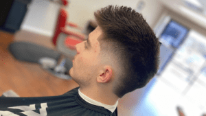 A person with a short, spiky hairstyle and a fade on the sides sits comfortably in a barbershop chair at one of the great barbershop spots in Bryan, TX.
