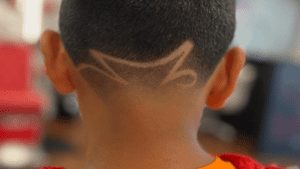 A curved line design is expertly shaved into the short hair on the back of a persons head, showcasing the skill found at great barber shops near me.