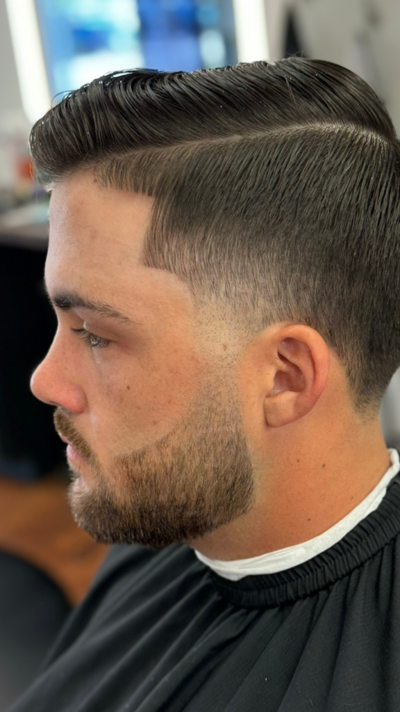 Man with trimmed beard and neatly styled hair at a barbershop in Bryan, TX.