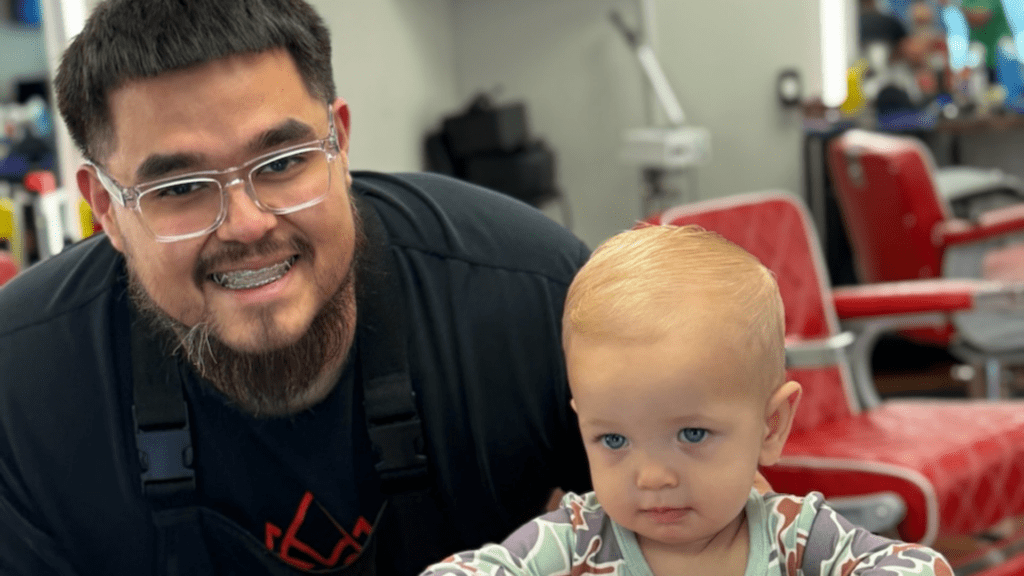 Smiling kid and barber after kids haircut at Kingdom Barber Studio.